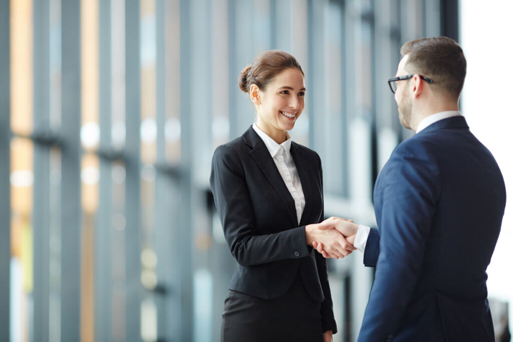 Young smiling businesswoman giving handshake to foreign business partner at meeting